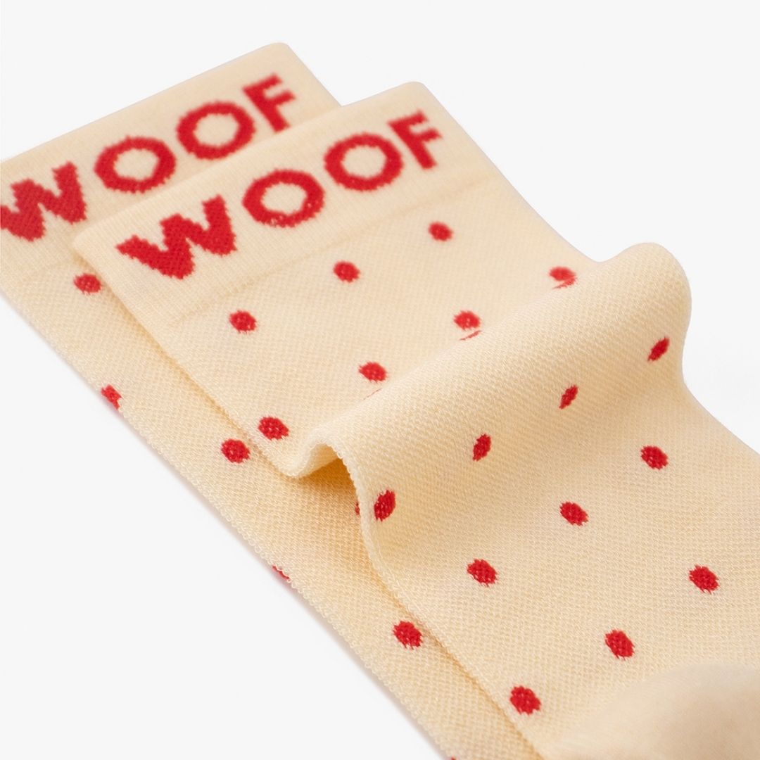 Polka Dots Bamboo Crew Compression Socks folded neatly to highlight the bold red woven "WOOF" cuff bands and the polka dot knit pattern layout.  